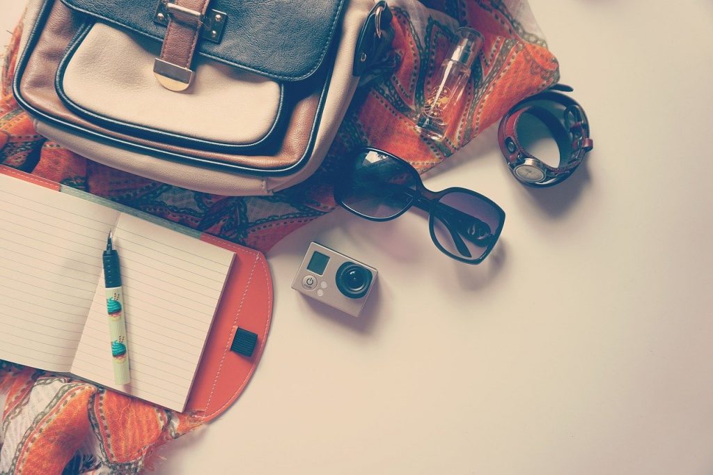 A bag, scarf, camera, sunglasses and watch on the floor