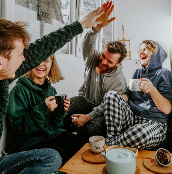 A group of friends relaxing, drinks cups of coffee and having a laugh