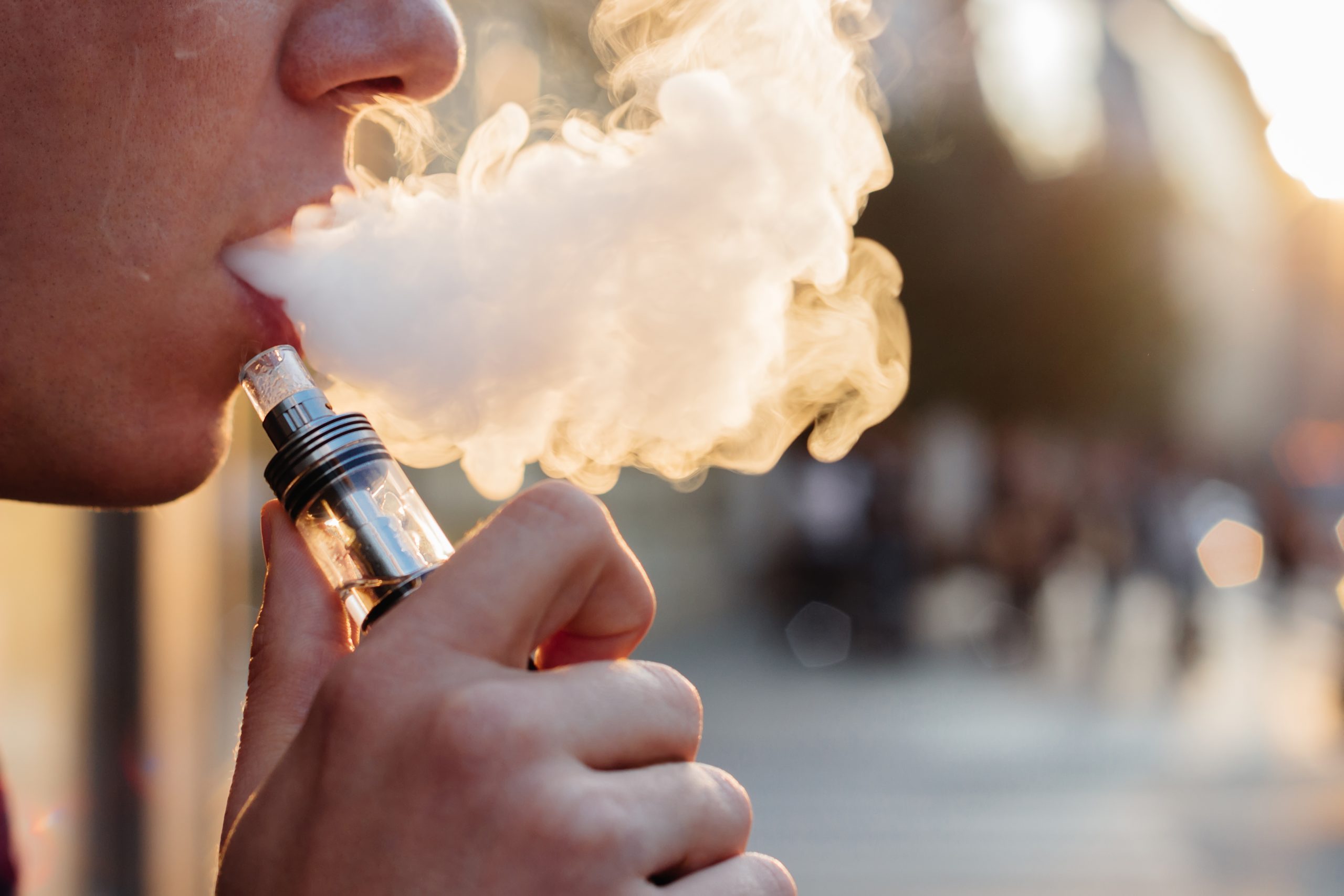 man using vape or electronic cigarette against the background of the city